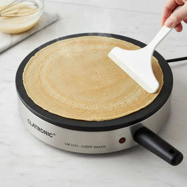 Close-up of Clatronic CM 3372 crepe maker with non-stick surface and batter spreader.