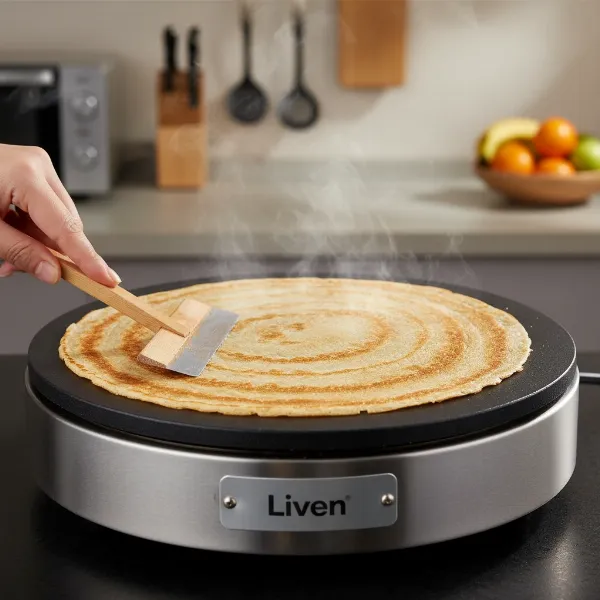 Close-up of a thin crepe being spread on a Liven Electric Baking Pan.