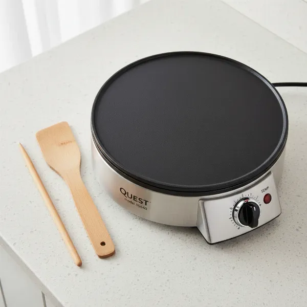 Quest electric crepe maker with wooden batter spreader and spatula on a clean surface
