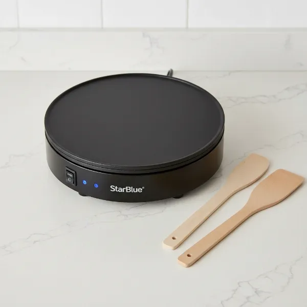 StarBlue crepe maker with included wooden batter spreader and spatula on a kitchen counter.